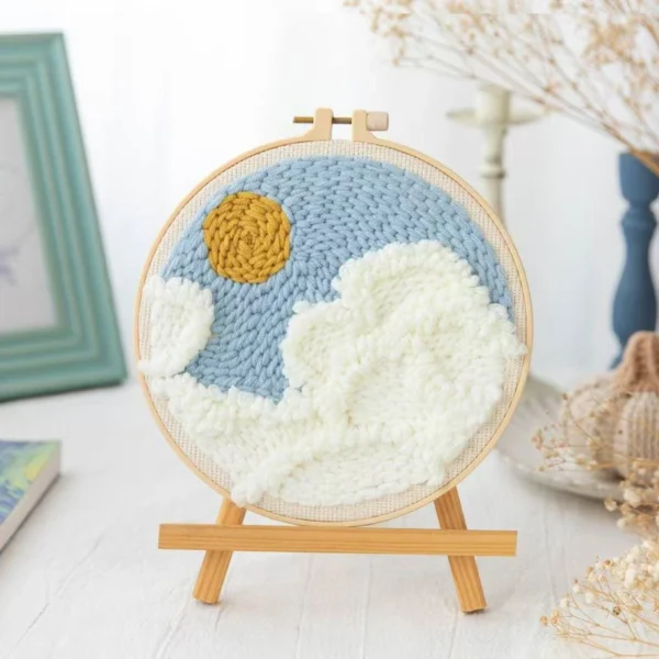 Punch Needle Hoop Kit for Beginners - Blue Sky & Clouds Design Beginner punch needle hoop art with blue sky, white fluffy clouds and yellow sun on wooden easel, craft kit