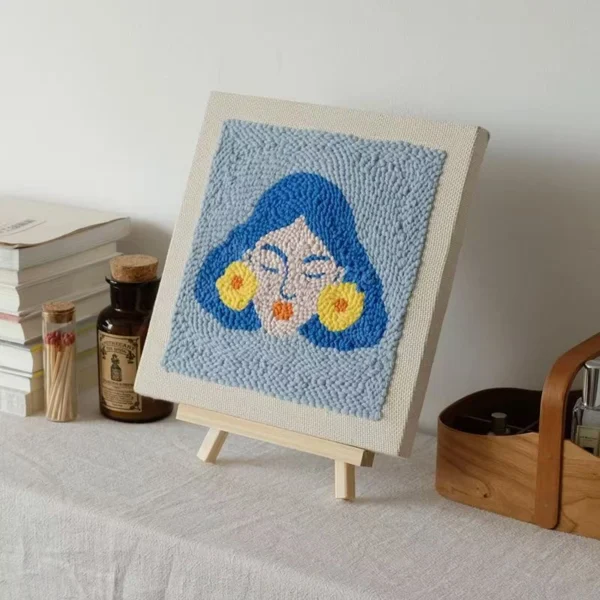 Frida Kahlo Wall Art Punch Needle Abstract Portrait on Easel Frida Kahlo wall art punch needle piece on easel showing blue-haired portrait with yellow flower earrings
