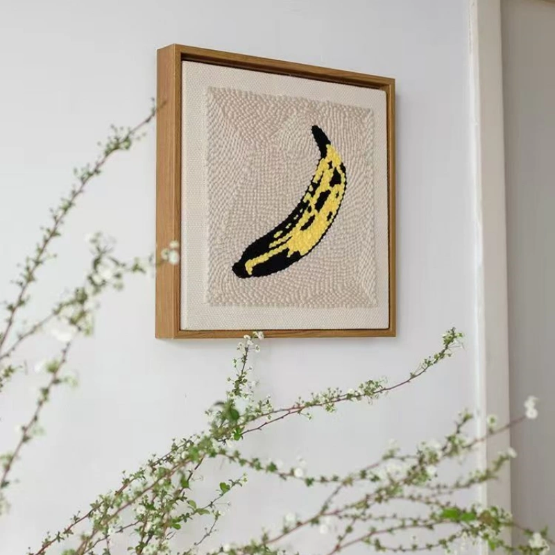 Andy Warhol Banana Wall Art - Pop Art Meets Nature Styling Andy Warhol banana punch needle art in wooden frame on wall with green botanical branches, artistic home styling