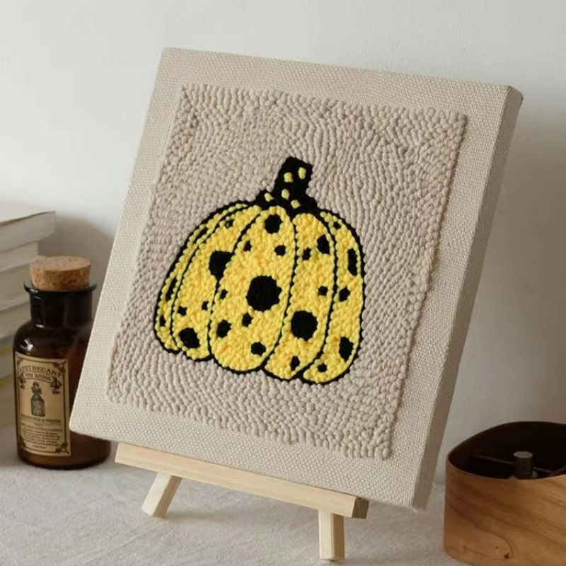 Yayoi Kusama Pumpkin Punch Needle Wall Art Kit - Polka Dot Canvas Design Yellow polka dot pumpkin punch needle art on beige canvas displayed on wooden easel