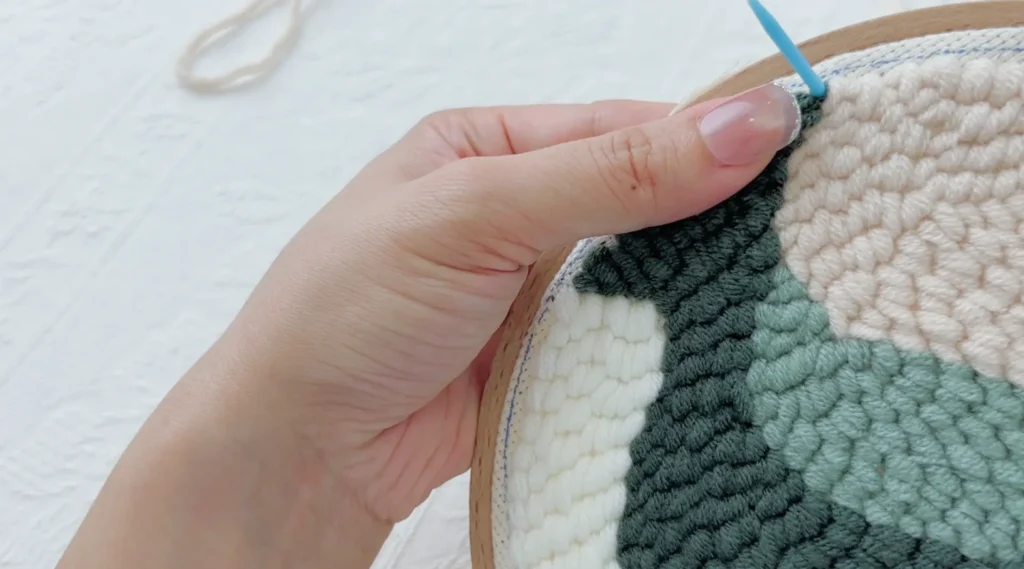 Bringing the plastic needle from the back to the front near the finished design edge.