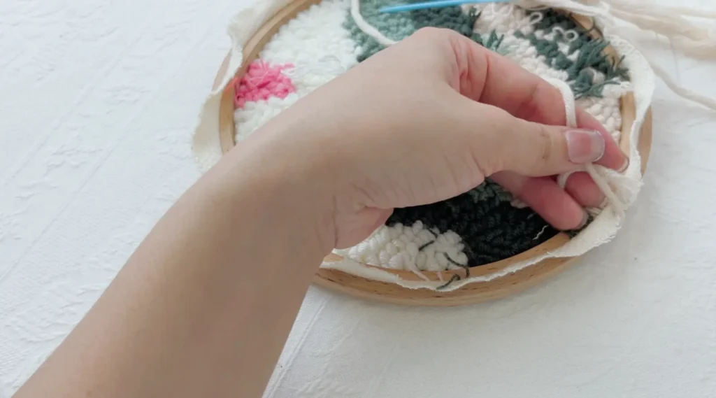 Tying a cross knot on the back of the hoop to secure the starting yarn.