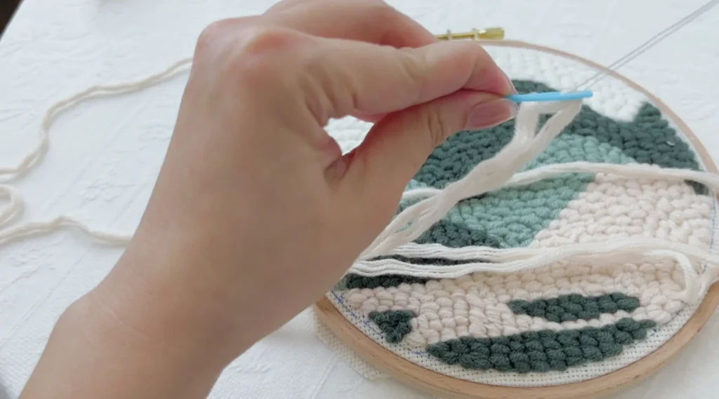 Threading yarn through a plastic needle using a threader, without tying a knot.