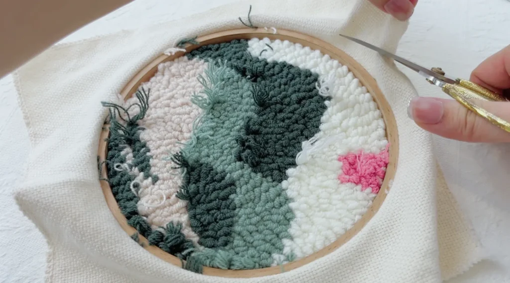 Trimming excess base fabric along the outer edge of the hoop, leaving a small allowance—one detail you should not overlook in this hoop edge finishing tutorial.