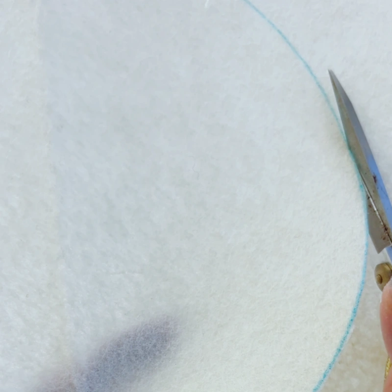 Cutting out the felt backing circle with scissors.
