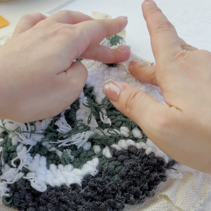 Pressing the base fabric inward against the glued area on the back of the embroidery using a firm, controlled motion.