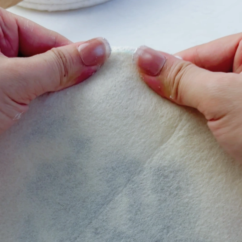 Attaching the cut felt backing to the embroidery back and pressing firmly.