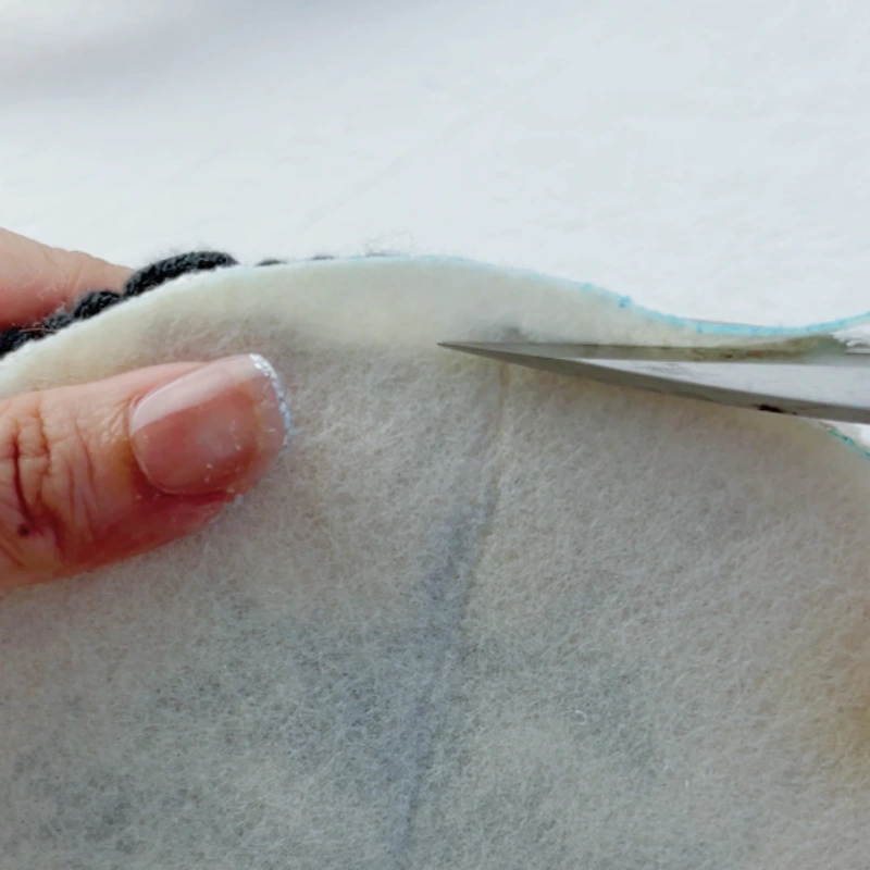 Trimming excess felt along the embroidery edge.