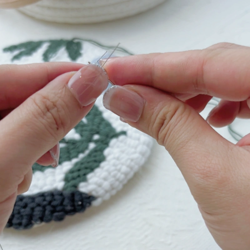 Passing the threader through the eye of a steel sewing needle.