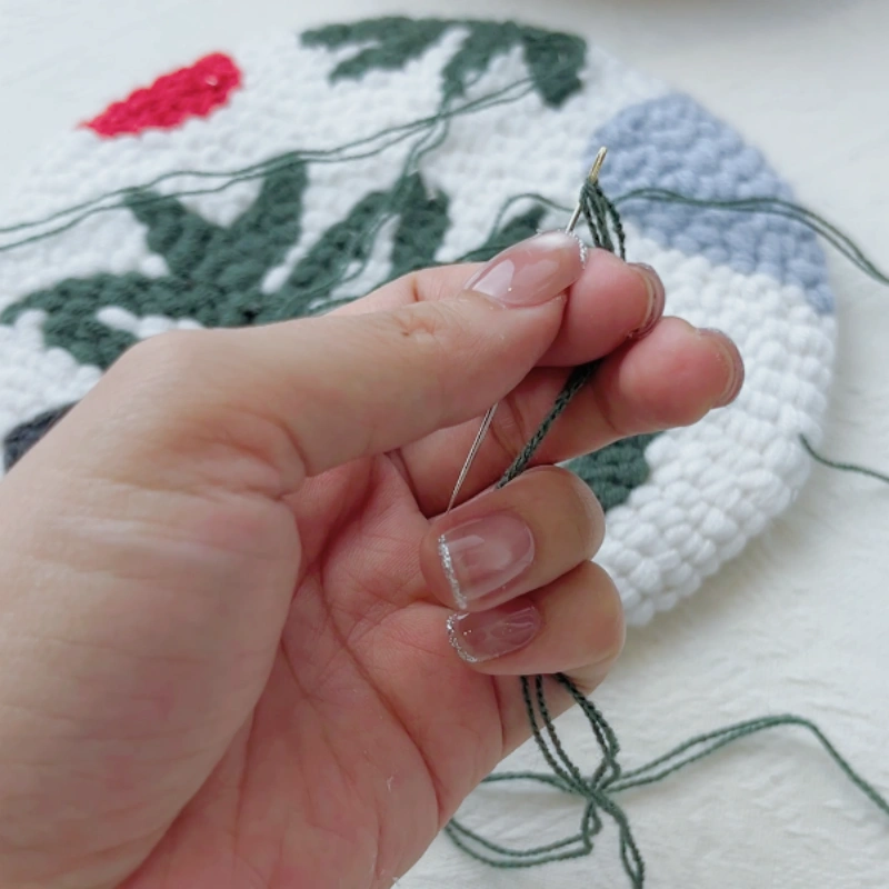 Sewing needle threaded with doubled yarn, without a knot.