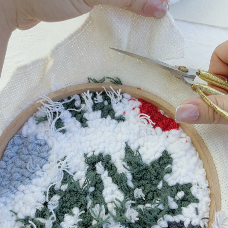 Trimming the base fabric along the outer edge of the hoop, leaving about 3 cm allowance.