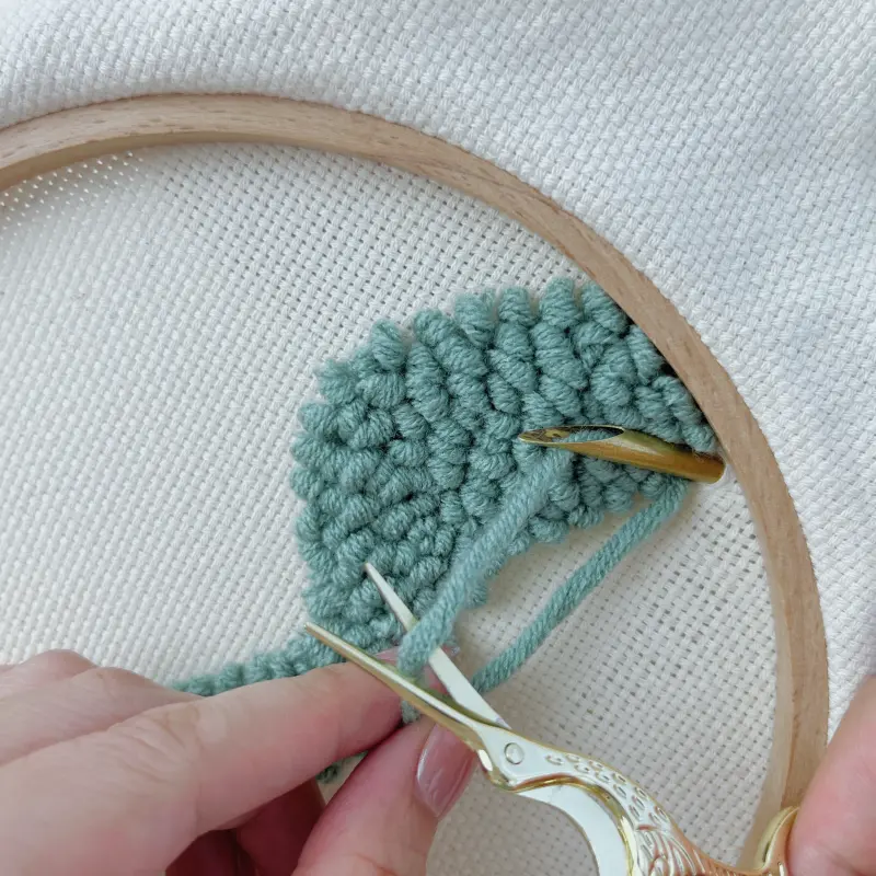 Finishing green block – punch needle tip still in fabric, pull 3–5 cm yarn from back and trim
