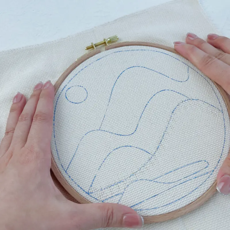 Placing the fabric flat and centered over the inner hoop before securing.