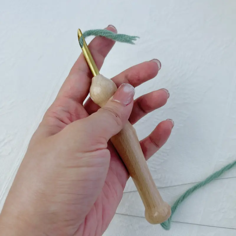 Leaving a short yarn tail extending from the punch needle tip before starting the first stitch.