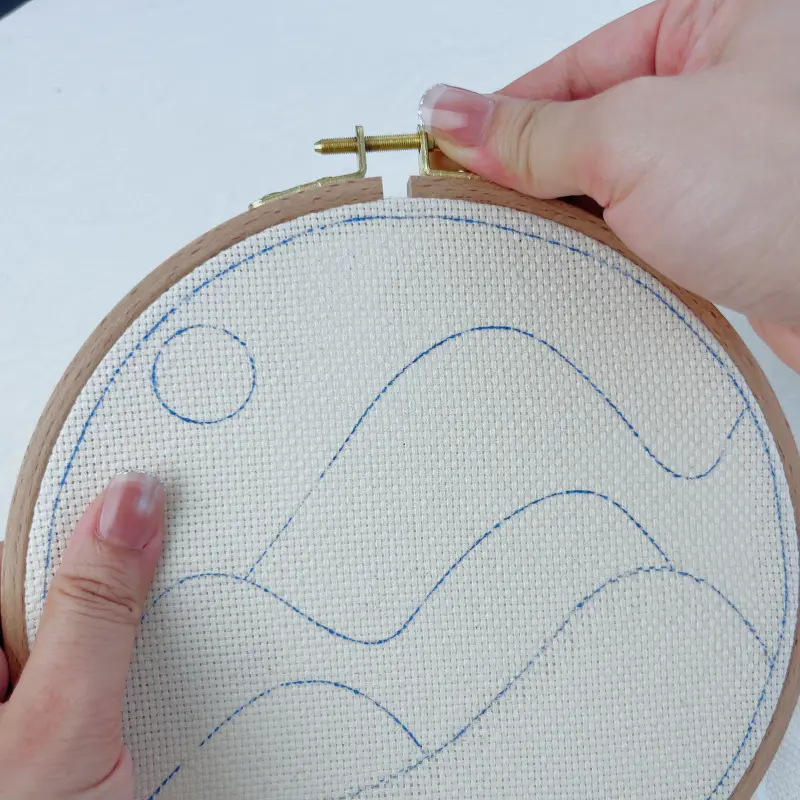 Placing the outer hoop back and preparing to secure the fabric.