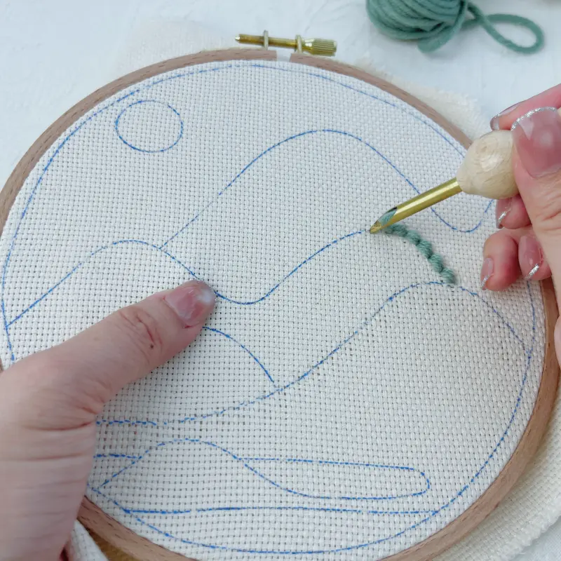 Punching continuously along the pattern while keeping the needle tip close to the fabric surface and facing the direction of stitching.