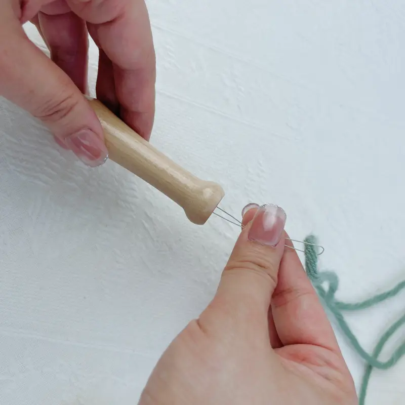 Pulling yarn through the punch needle body using the threader.