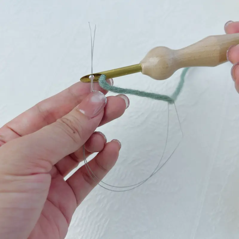 Threading yarn through the small hole at the needle tip — a key technique in any beginner punch needle tutorial.